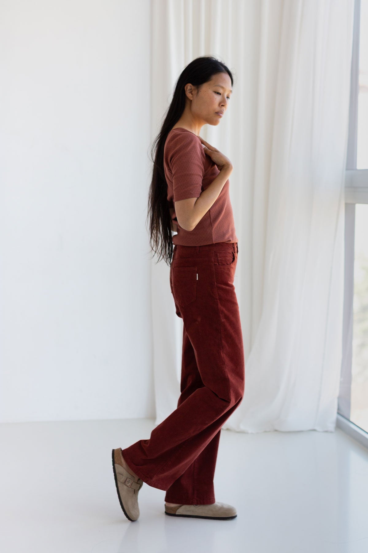 Side view of a woman wearing a brown pointelle top and corduroy pants.