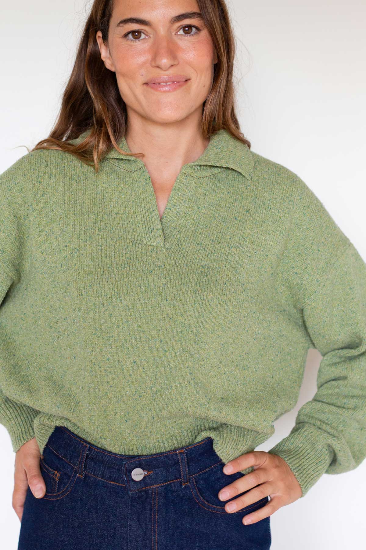 Woman wearing a matcha green polo collar knit sweater and blue jeans.