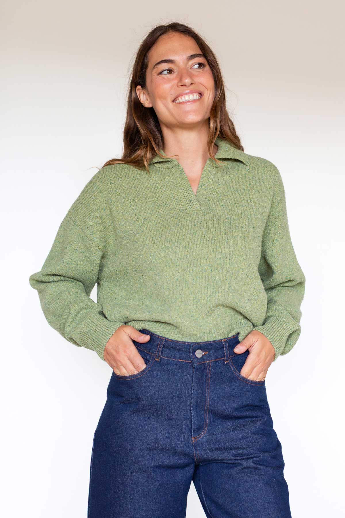 Woman posing with hands in pockets wearing a matcha green polo knit sweater.
