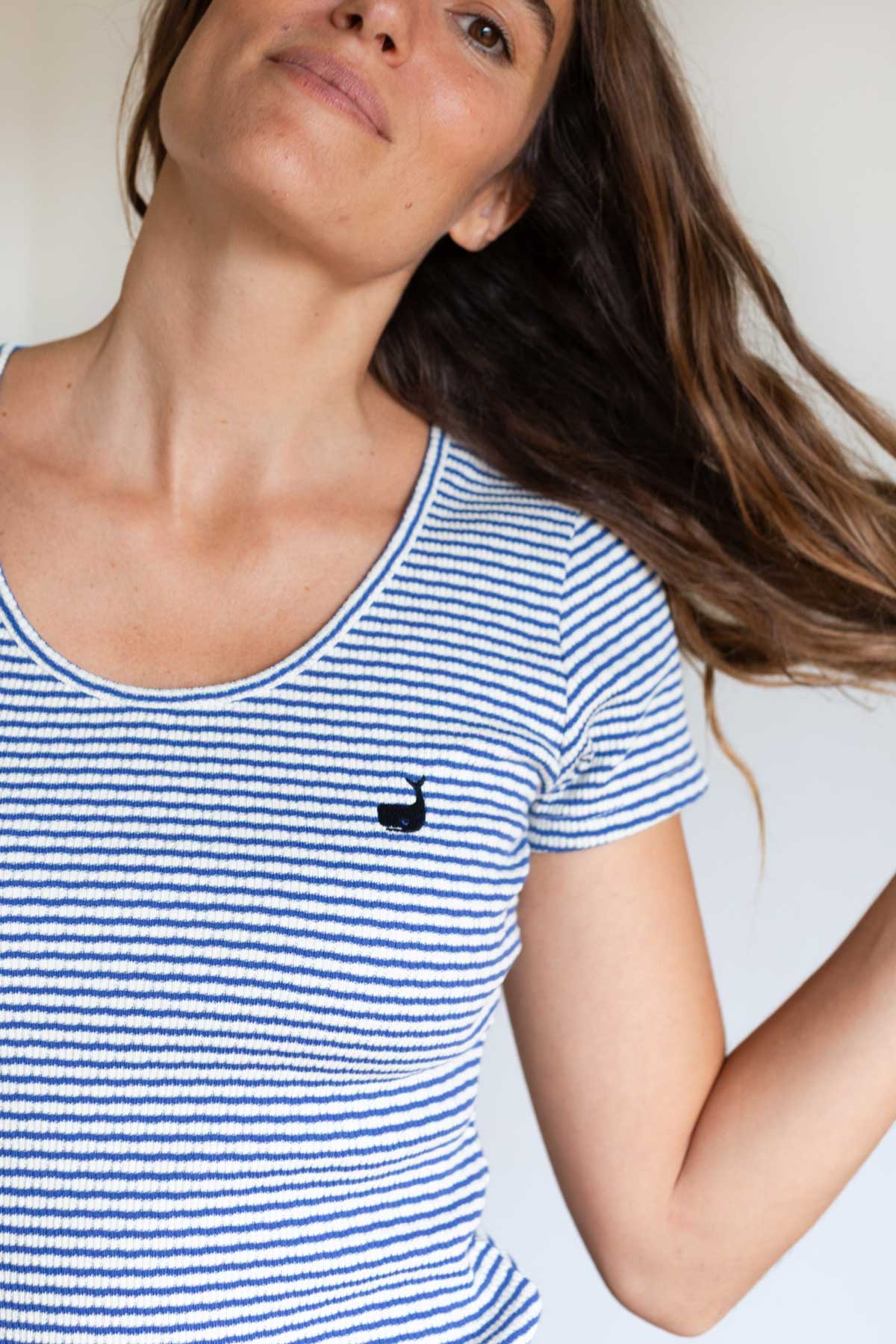 Close-up front view of a blue striped scoop neck top with a small whale logo.
