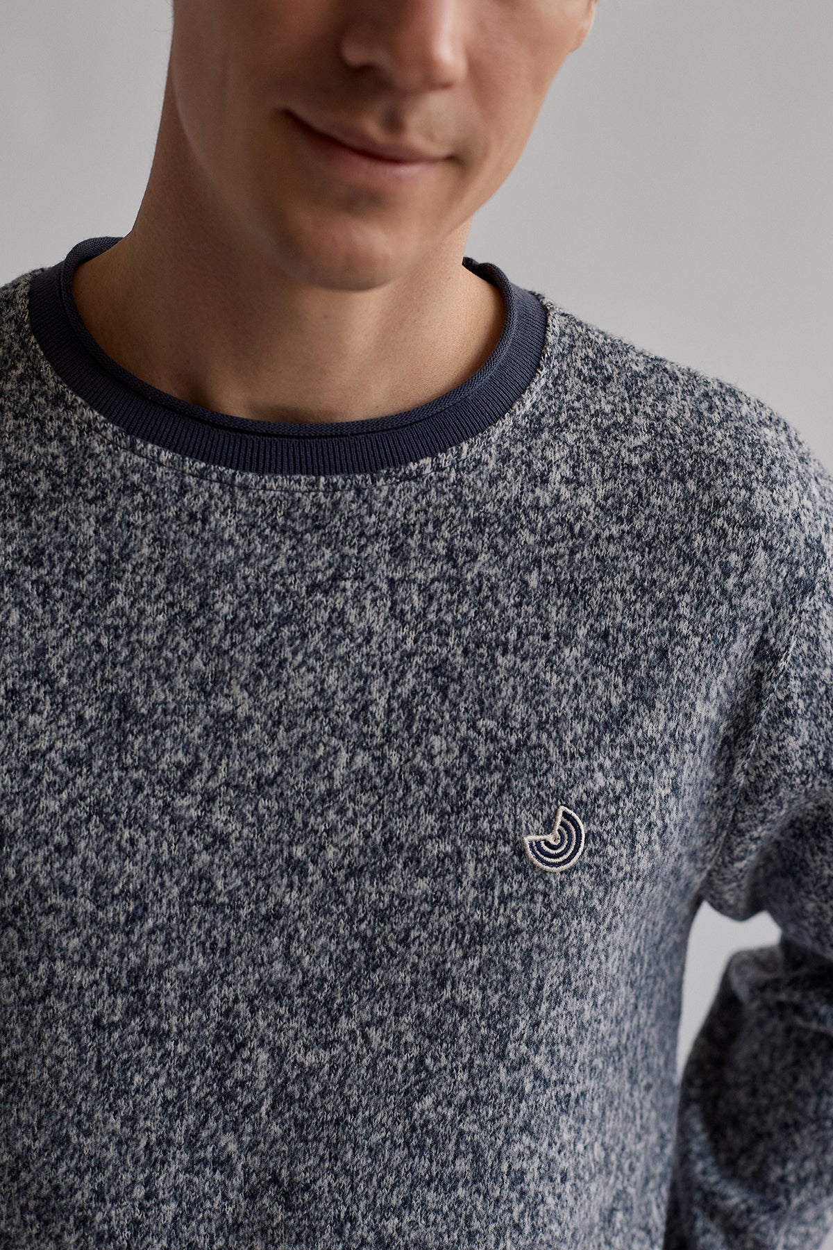 Close-up of embroidered logo on navy sweatshirt