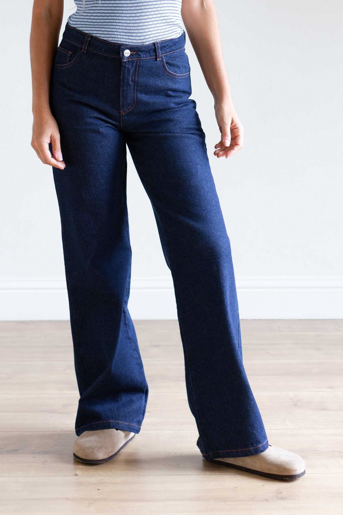 Front view of a woman wearing dark blue straight-leg organic cotton denim pants.