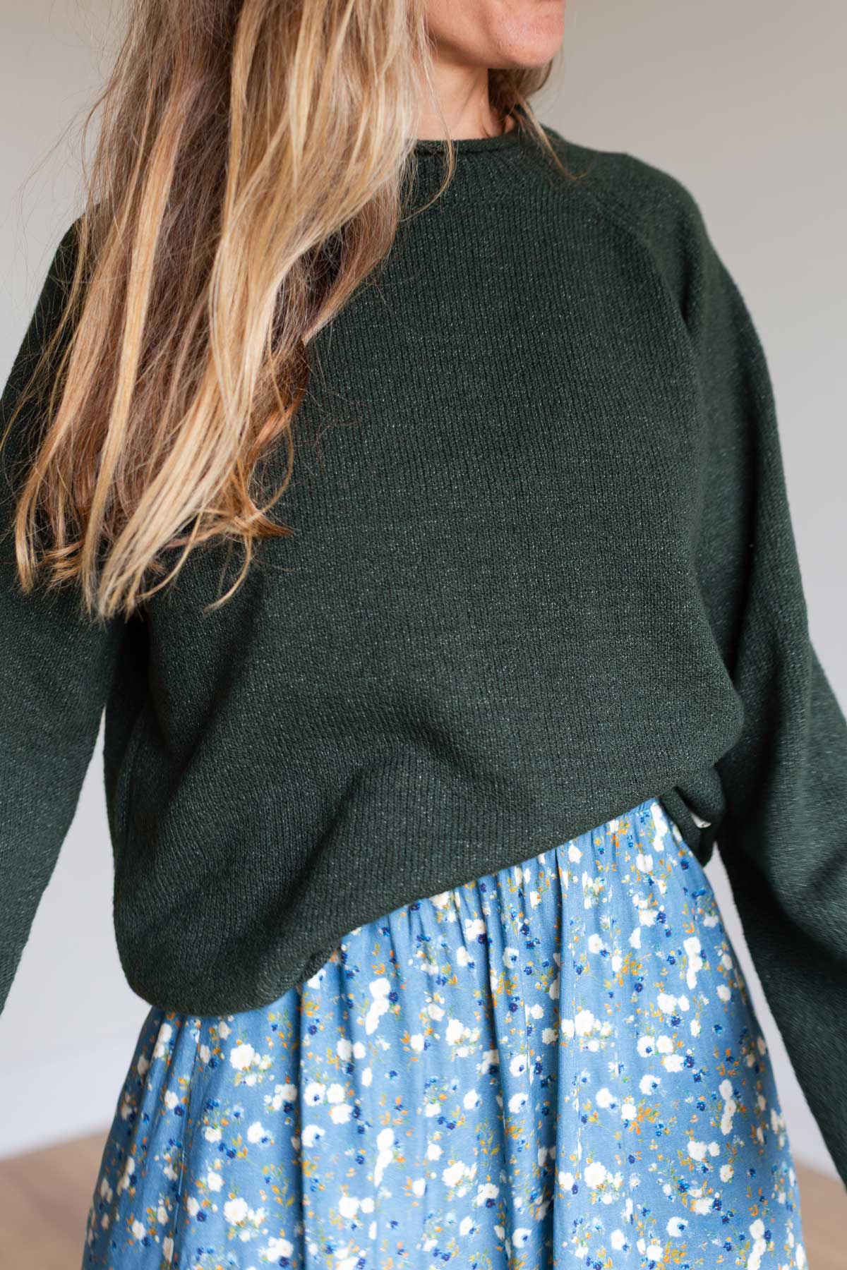 Close-up detail of the textured dark green organic cotton knit sweater.