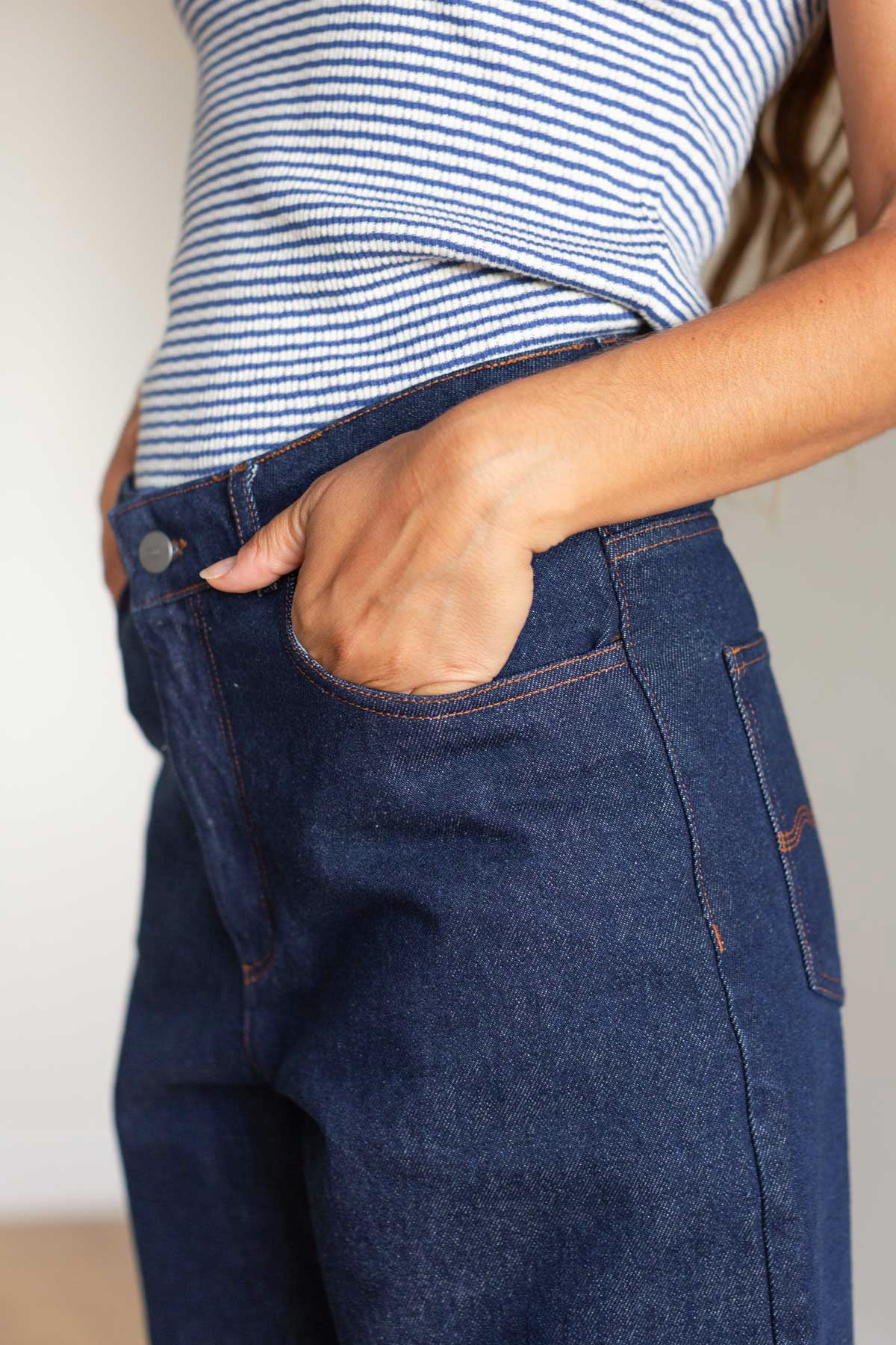 Close-up side view showing a hand in the pocket of dark blue wide-leg jeans.