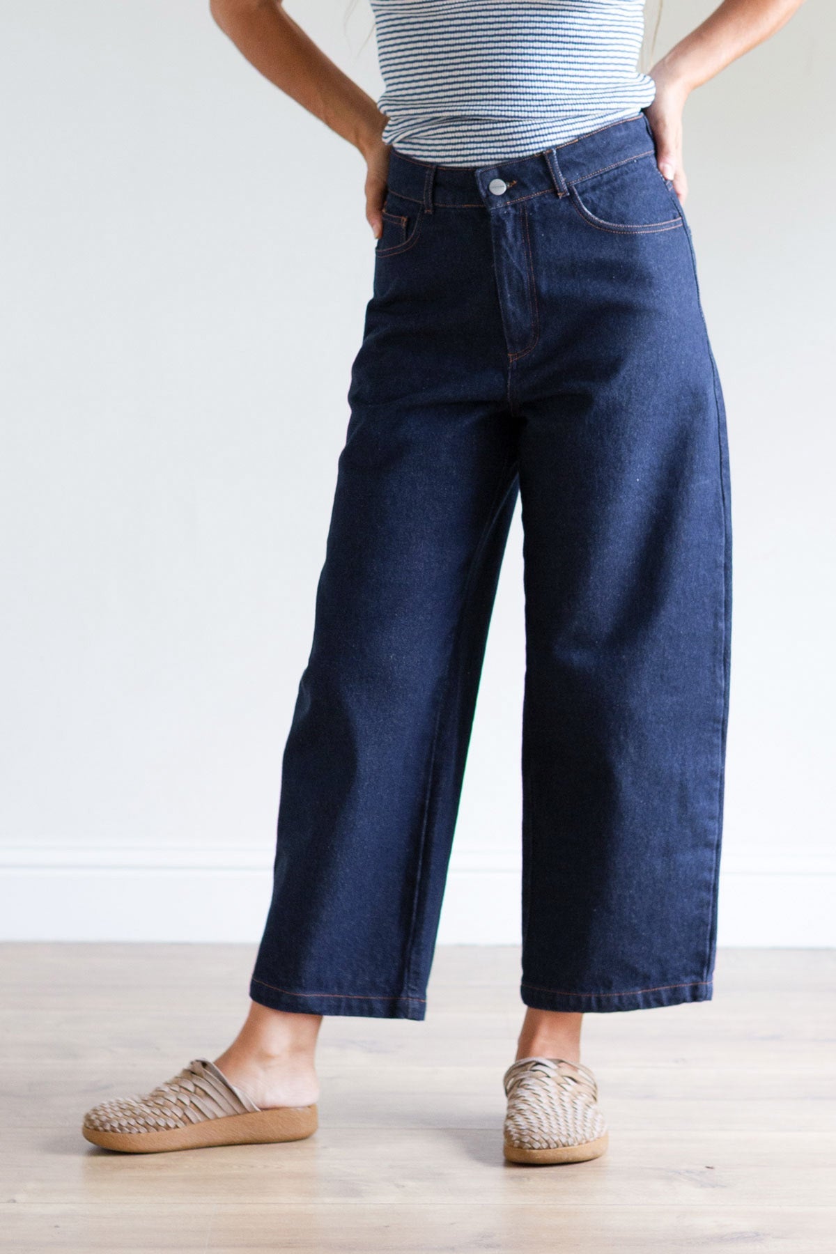 Front view of a woman wearing high-waist wide-leg cropped dark blue denim pants.