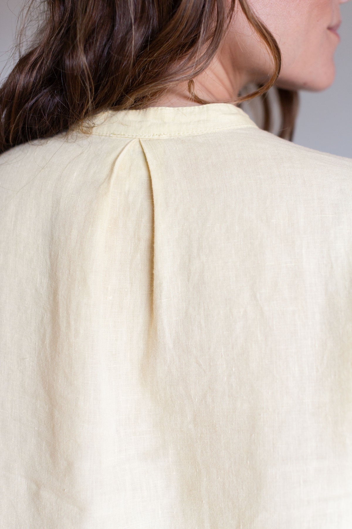 Back view detail showing the pleat on a gardenia yellow linen shirt.