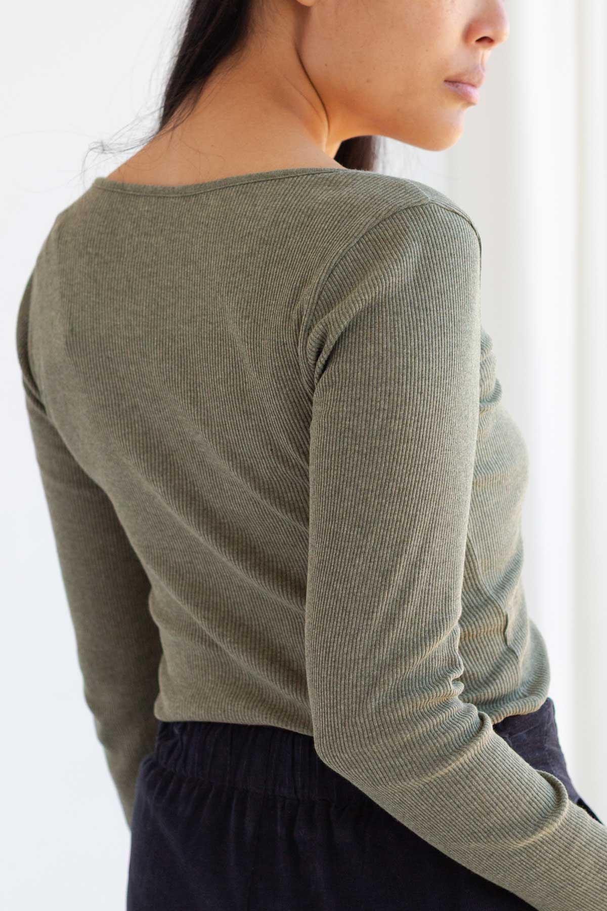 Back view of woman wearing an olive green long sleeve top.