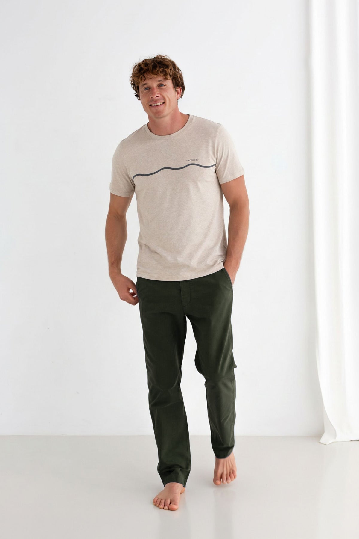 Man wearing a beige t-shirt and dark moss pants.