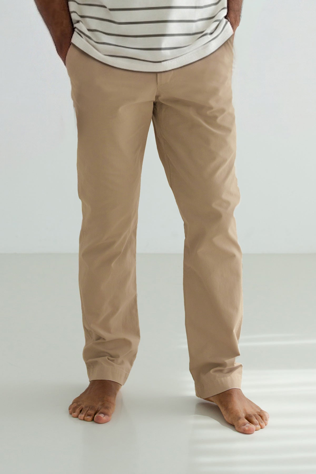 Man wearing beige pants his with hands in his pockets.
