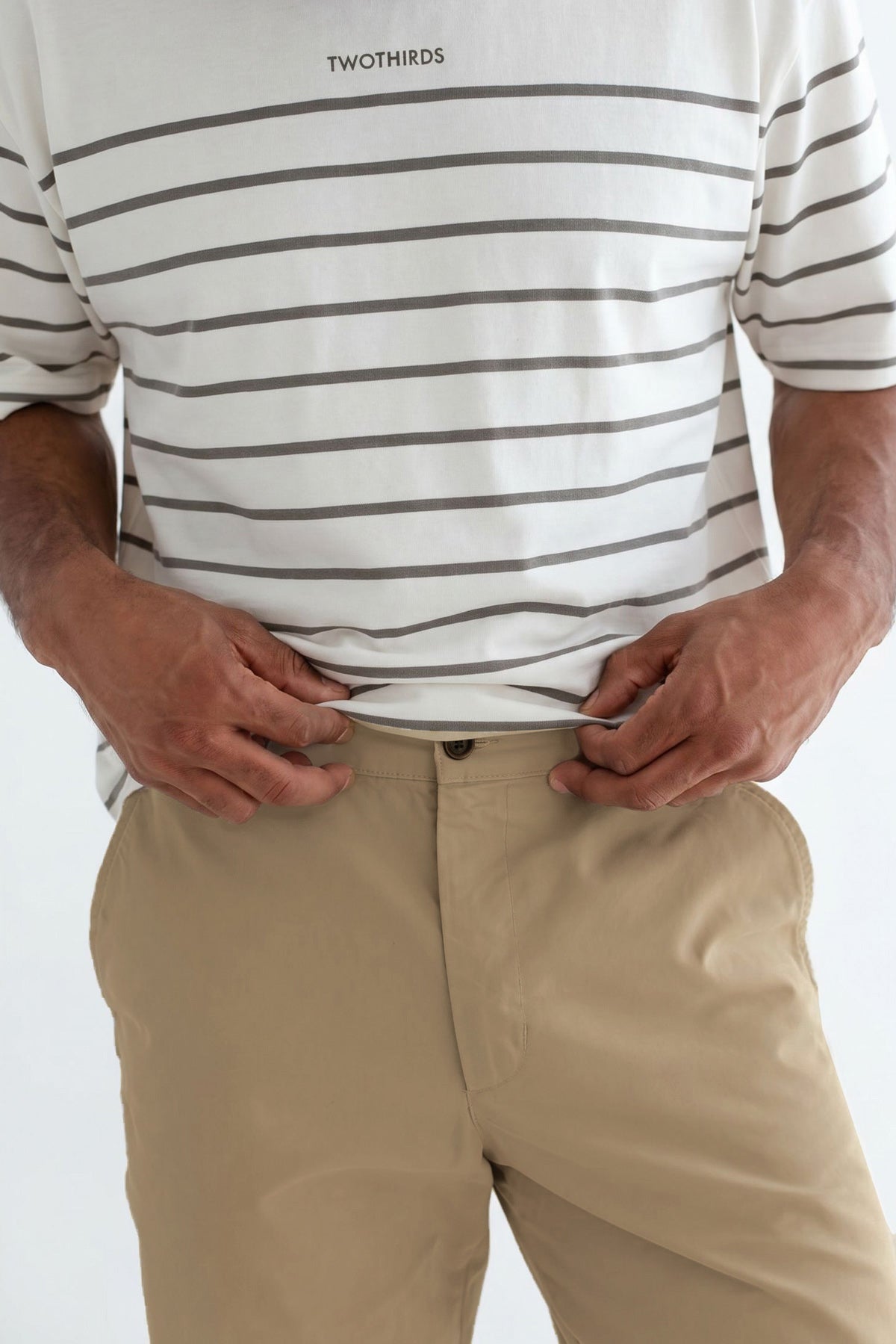 Man wearing a striped shirt tucked into beige pants.