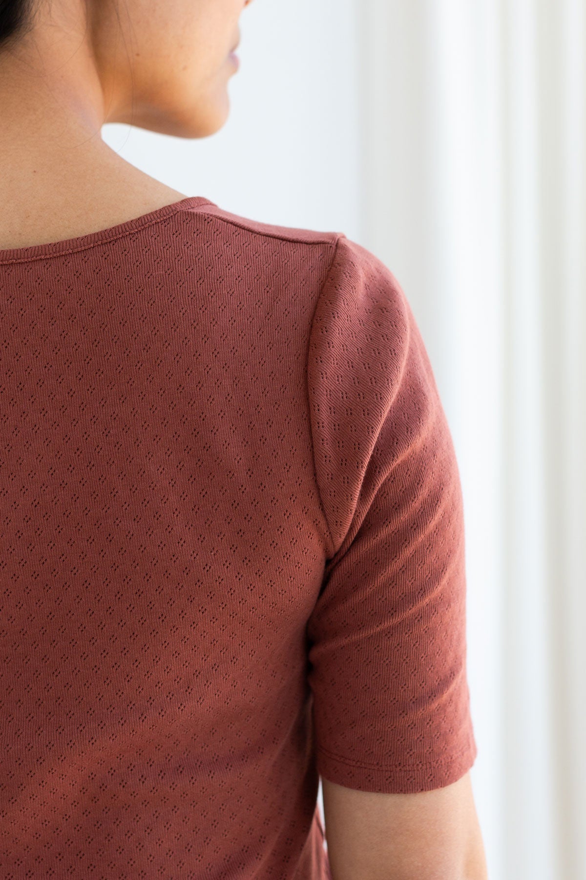 Back view detail of a woman wearing the brown organic cotton pointelle top.
