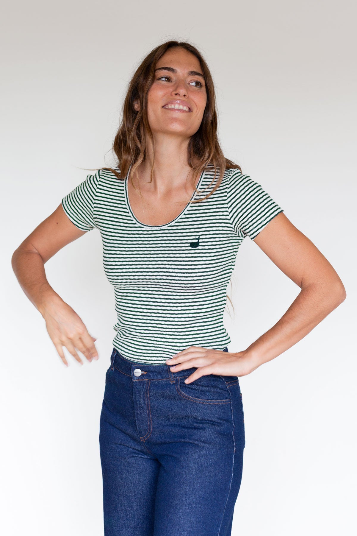 Woman posing with hands on hips wearing a dark green striped ribbed top.