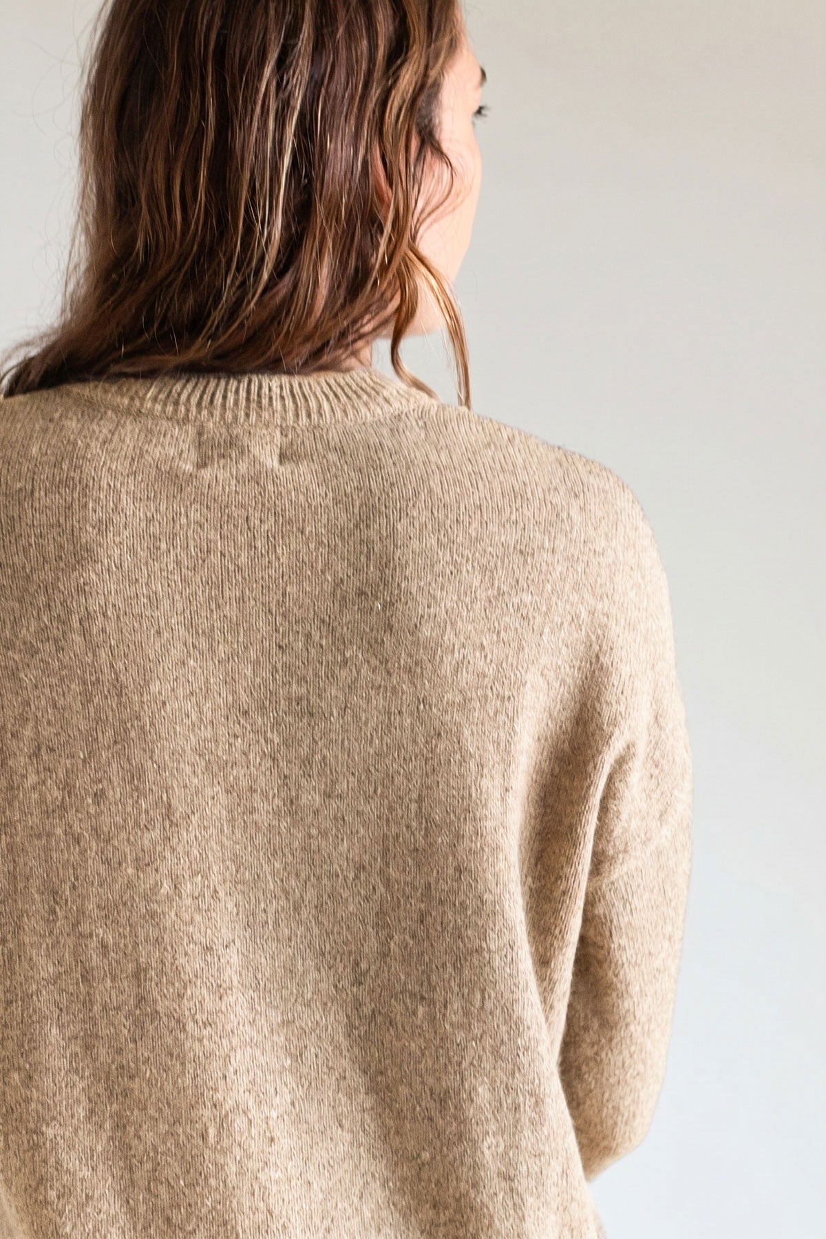 Back view detail of a textured beige relaxed-fit knit sweater.