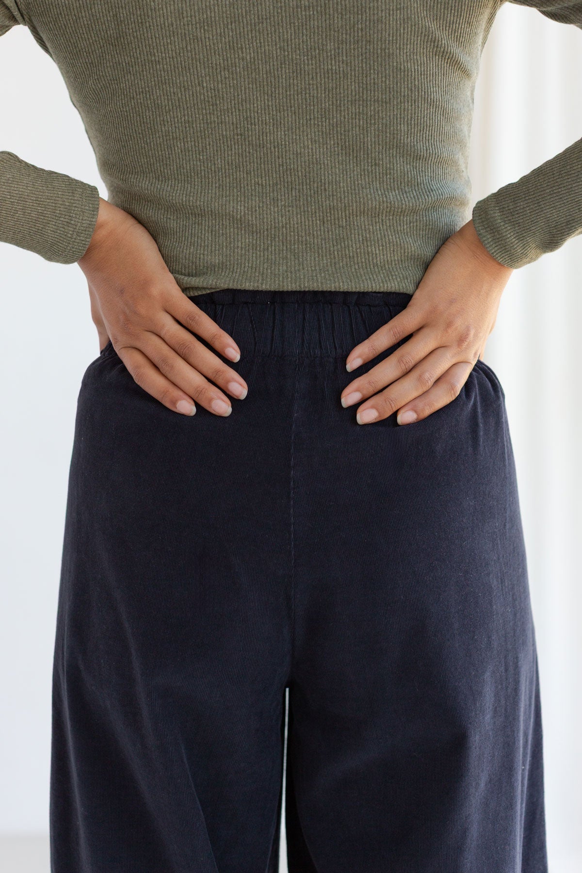 Back view detail showing the flexible rubber waistband on midnight blue micro cordury pants.