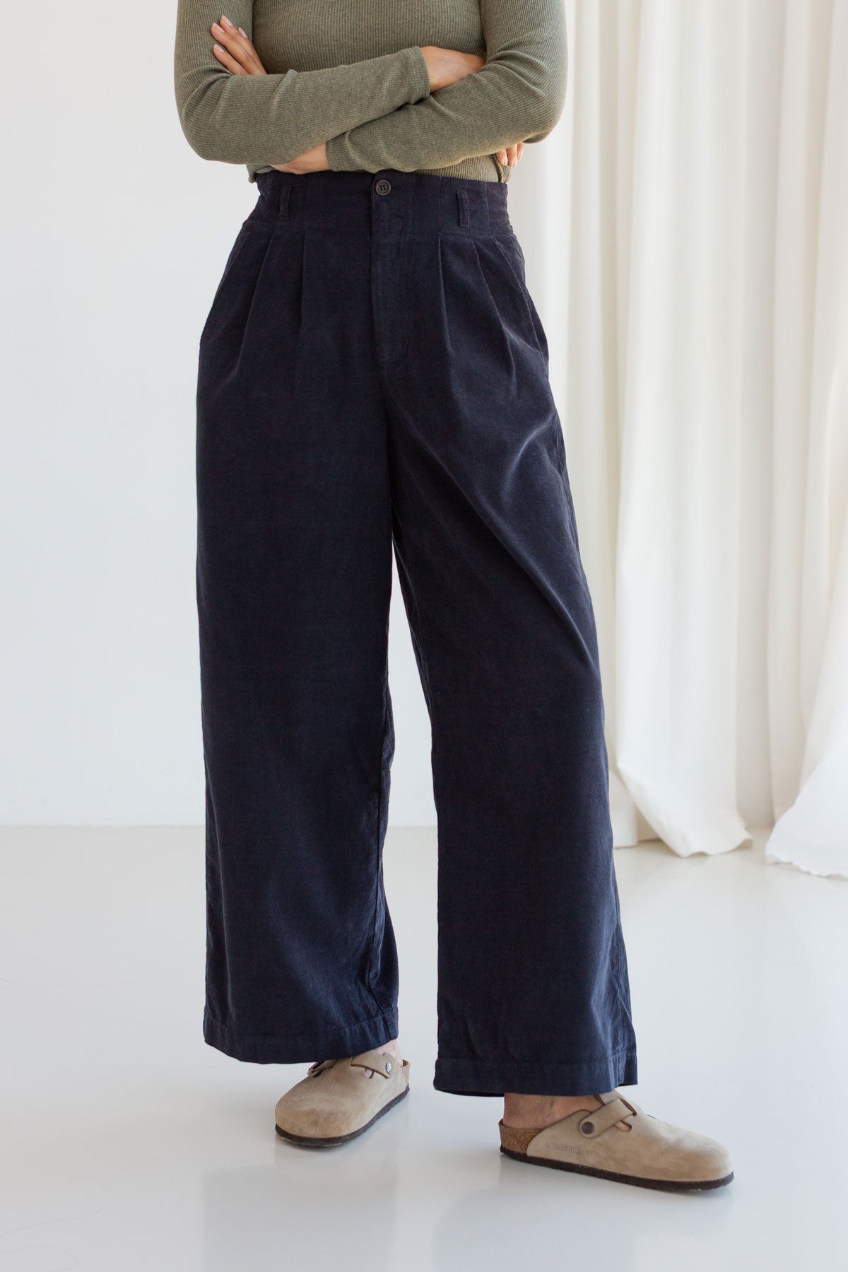 Front view of a woman wearing midnight blue wide-leg micro corduroy pants.