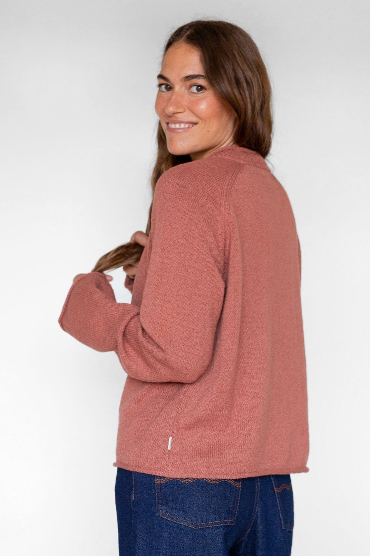 Back view of a woman wearing a rose-colored raglan knit sweater.