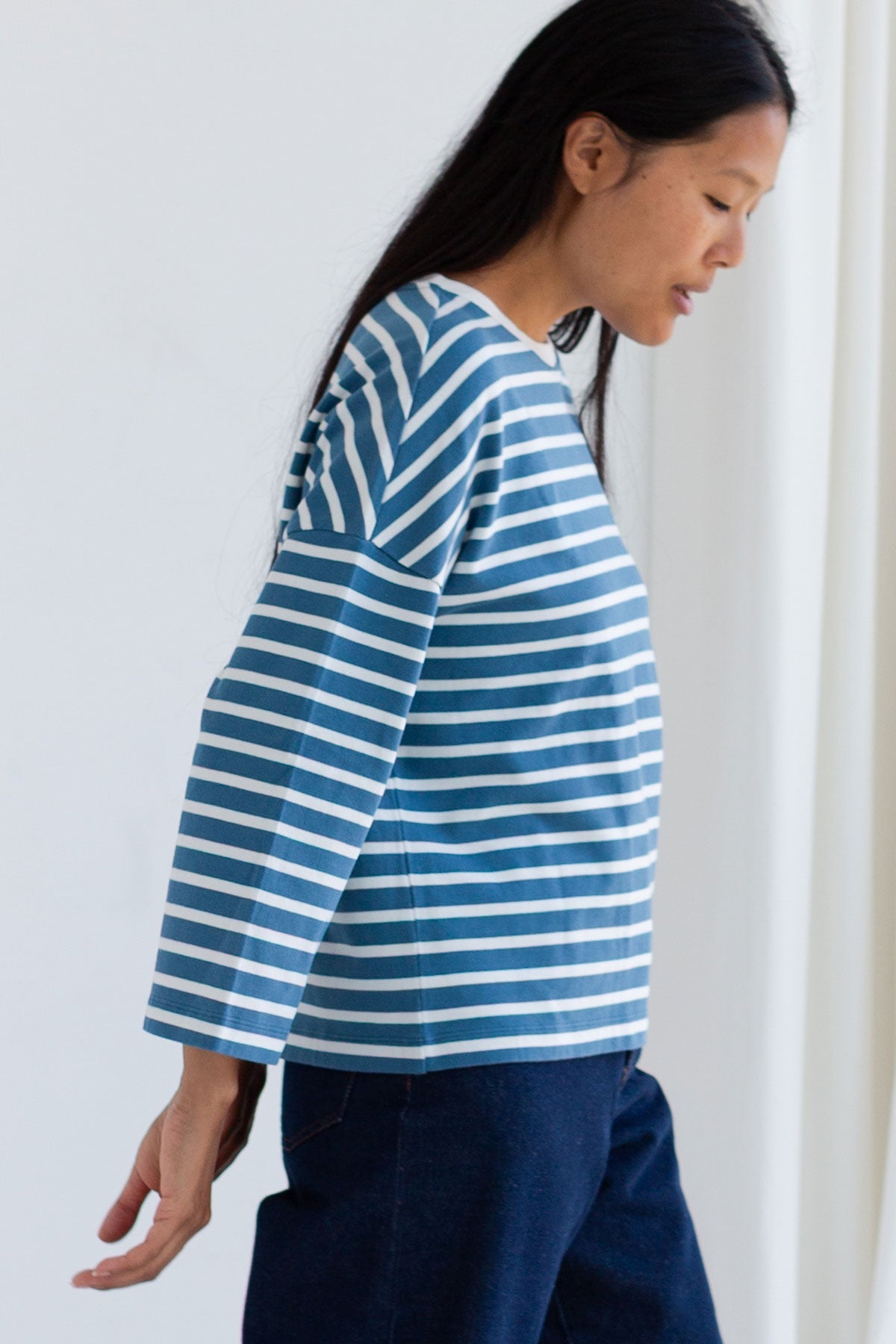 Side profile of woman wearing a dusty blue and white striped shirt.