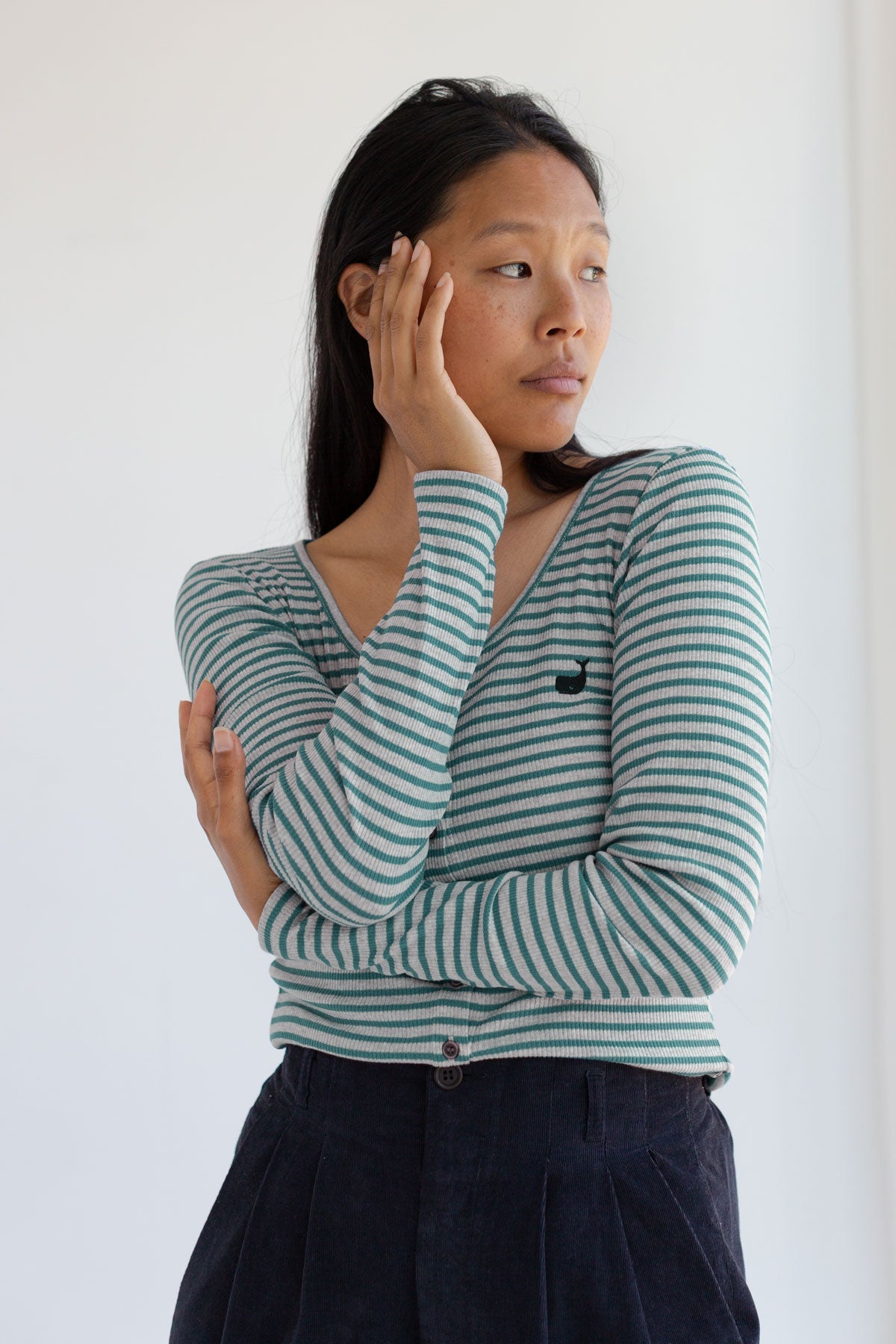 Woman posing with arms crossed wearing an alga green striped ribbed long sleeve top.