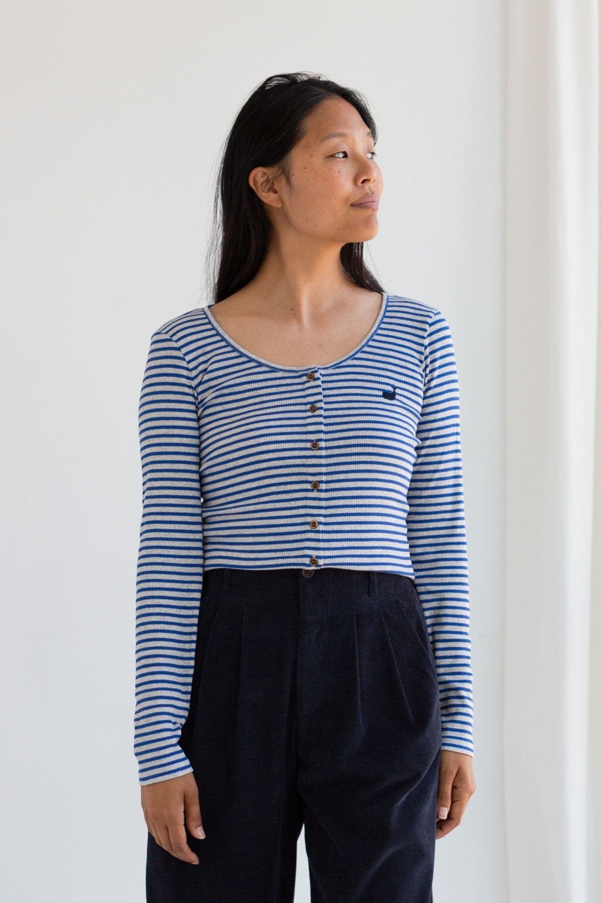 Woman wearing a royal blue striped ribbed long sleeve top with buttons.