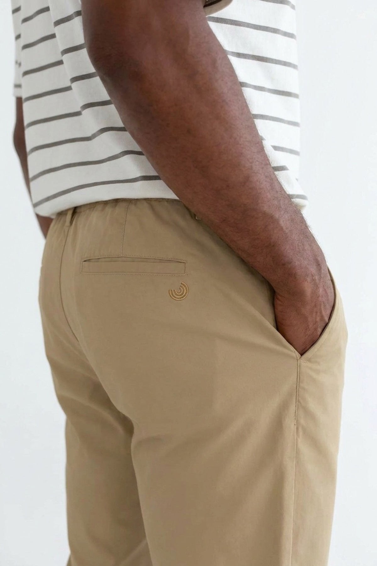 Back view of beige pants with a hand in pocket.